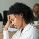 Woman with a painful expression on her face resting her head against her hand