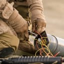 Close-up shot of Soldier Defusing a Bomb by Cutting a Wire During Military Operation in Desert Environment