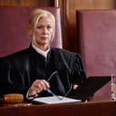 Portrait of a serious, mature female judge wearing a black robe while seated at the supreme court.