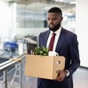 Man in suit getting ready to leave the office with his personal belongings in a card box