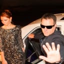 bodyguard shielding a female celebrity from paparazzi while exiting a limousine