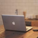 silver MacBook on a wooden table in a cafe