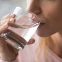 close-up of a young woman drinking a glass of water to stay hydrated