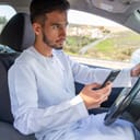 clos-up of a young man using a mobile phone while driving