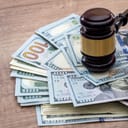 close-up of a wooden gavel with US dollars on a desk