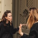 Two women arguing intensely outdoors on the street near a door