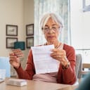 A senior woman holding medicine and reading about side effects