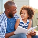 Father and daughter reading a book together and sharing a laugh