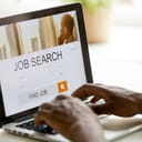 African man browsing work opportunities online using job search computer app, black jobless seeker looking for new vacancies on website page at laptop screen, recruitment concept, rear close up view
