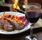 Pasta with lambchops next to a glass of red wine
