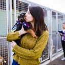 Young woman with worker choosing which dog to adopt from a shelter