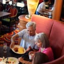 Three people sitting down in a booth having their breakfast in a restaurant
