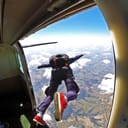 A person jumping out of an airplane with a parachute on their back