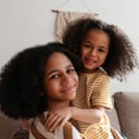 Two sisters embracing while seated on a sofa