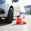 close-up on a car's tire and one orange cone knocked down