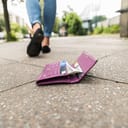 a lost wallet on the sidewalk with female walking away in the background