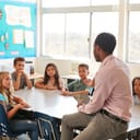 Male teacher leading a class discussion with elementary school children