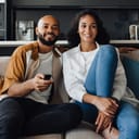 Young cheerful african american couple watching TV while sitting on sofa at home