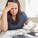 Brunette woman looking worried over bills in the kitchen