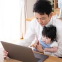Father with a baby in his lap looking at a laptop display