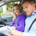 Trainee and driving instructor inside a car examining papers