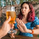 woman in a bar refusing a glass of beer that a man is offering