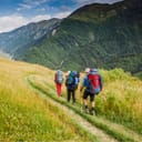 Three hikers walking down a trail in the mountains