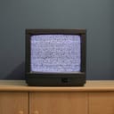 old analogue TV on a wooden drawer displaying static noise, indicating no signal