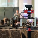 Closeup smart mobile phone taking Live over Speakers on the stage with Rear view of Audience in the conference hall or seminar meeting, technology live streaming and broadcast concept
