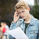 A teenage boy looking worried as he reviews his unsatisfactory exam results.