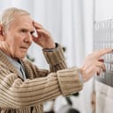 Senior man touching his head while looking at a wall calendar