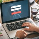 A person typing in their login information on a laptop