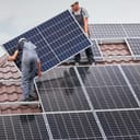 Workers installing solar panels on a house roof