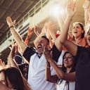 Crowd of sports fans cheering during a match in stadium.