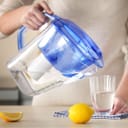 Person pouring water from a container with a filter into a glass