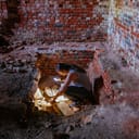 An archaeologist, equipped with a flashlight, carefully examines the old crypt beneath a church, delving into its historical secrets and mysteries.