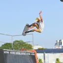 A young man performing tricks while skateboarding in skate part.