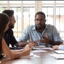 A serious young manager talking with with his coworkers during a meeting