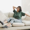 A woman waking up smiling from a nap on the couch