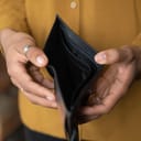 Close up young African American unemployed woman holding opened empty black leather wallet