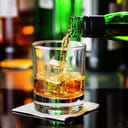 Whiskey pouring from a bottle into a glass in a bar.