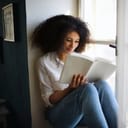 Portrait of young woman with book indoors at home, reading.