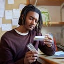 a young man is checking the box of the pills he needs to take