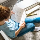 woman sitting on the floor and reading manual for building a bookcase in her room