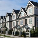 A row of townhouses with beige facade and white doors and windows