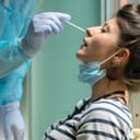 A nurse taking a nose swab from a female patient