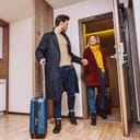 A couple dragging their suitcases entering a hotel room