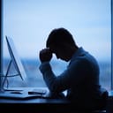 a tired businessman sitting at his desk with a computer in front of him