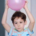 A child creating static electricity by rubbing a balloon on their hair
