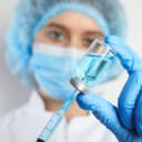 Health worker loading up a syringe from a bottle